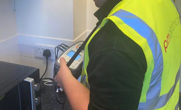 PM Electrical electrician performing EICR test on appliance
